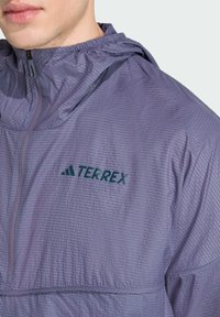 Purple Terrex hooded jacket featuring a grid texture, a front zipper, and a dark green logo. Fabric appears lightweight and smooth.