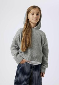 Sweat à capuche en tricot gris avec une coupe décontractée, des poignets et un ourlet côtelés, et une texture douce, associé à un pantalon rayé sombre.