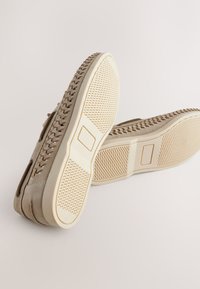 Chaussures en daim gris avec une semelle texturée et des accents beiges. Dotées d'un design à lacets et d'ouvertures latérales pour une meilleure respirabilité.