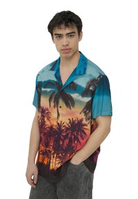 Camicia a maniche corte con bottoni, caratterizzata da un design di tramonto tropicale, con tonalità di blu e arancione, grafiche di palme e una texture di tessuto morbido.