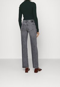 Jeans de tiro alto y pierna ancha en denim gris-negro; cuentan con bolsillos traseros, costuras en contraste blancas y detalles de dobladillo deshilachado.