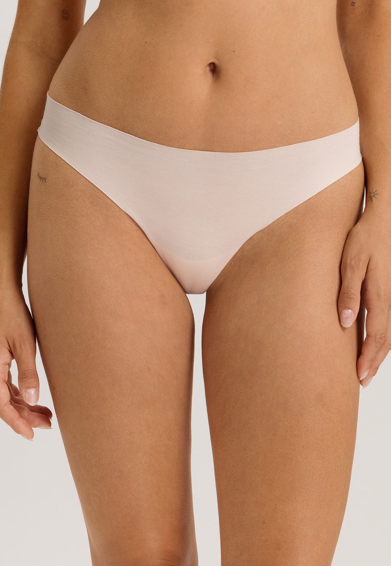 Lichtroze katoenen string met een zachte textuur, voorzien van een naadloze tailleband en een minimalistisch ontwerp voor comfort en flexibiliteit.