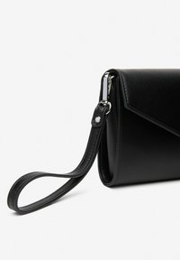 Sort læder clutch taske med en glat tekstur, vinkelagtigt design og en aftagelig rem. Udstyret med en sølvfarvet hardwaredetalje nær lukningen.