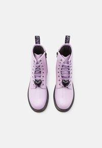 Liliowe lakierowane botki na kostkę z przednim zamkiem, czarnym akcentem w kształcie serca i fioletowymi sznurowadłami, z teksturowaną podeszwą i pętlą do zakładania.