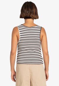 Černobílý pruhovaný bezrukávový top s žebrovanou texturou, kulatým výstřihem a přiléhavým střihem. Má rovný lem.