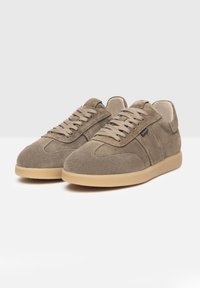 Beige Wildlederschuhe mit runder Zehenpartie, Schnürung vorne und minimalistischem Design. Gummisohle und kontrastierende Gummilaufsohle. Weiche Textur.