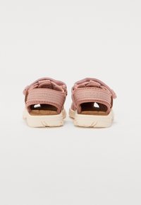 Justerbara rosa tygsandaler med en strukturerad innersula och lätt krämfärgad yttersula. Har spännen och öppen häl för bättre andningsförmåga.