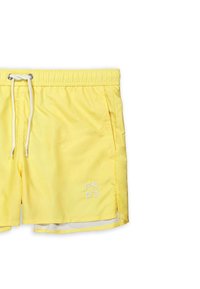 Pantaloni da nuoto gialli realizzati in materiale leggero, con vita regolabile tramite cordoncino, tasche laterali e un logo bianco nella parte bassa anteriore.