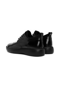 Zwarte leren sneakers met een glanzende afwerking, brogue-details en een zwarte rubberen zool met textuur. Voorzien van contrasterende zwarte veters en achterlussen.