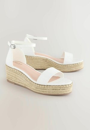 Sandalias de cuña blancas con una plataforma de yute trenzado, que cuentan con un upper de imitación de cuero suave, correa en el tobillo y un diseño de punta abierta.