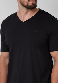 Zwarte v-hals t-shirt van katoen, met korte mouwen en een subtiele s.Oliver-logo geborduurd op de borst.