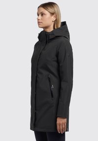 Parka imperméable noire avec capuche, dotée d'une fermeture éclair à l'avant, de poches latérales et d'une texture lisse. Cords de serrage réglables à la capuche.