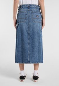 Denim midi-hame suoran leikkauksen, vaaleansinisen värin, viiden taskun, näkyvien ompeluiden ja logopatchin kanssa vyötärön lähellä.