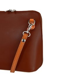 Bruine lederen tas met een gladde textuur, voorzien van een zilveren ritssluiting, een afneembare oranje band en bruine stikaccenten.