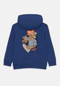 Chandail à capuchon bleu avec un graphique d'un chien portant une casquette, des lunettes et des écouteurs, tapant sur un clavier avec le texte "Écrire est ma passion".