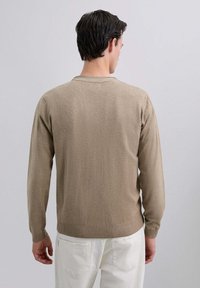 Suéter beige de manga larga con cuello redondo y dobladillo acanalado. Textura suave y diseño ajustado, mostrado desde la parte posterior sobre un fondo claro.