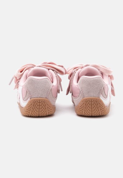 Paire de baskets pour enfants roses et beiges avec des lacets épais, vue de dos montrant des semelles brunes texturées.