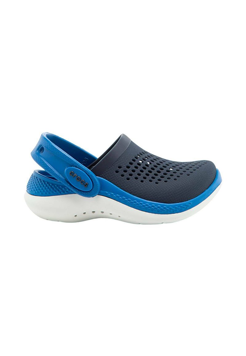 Zuecos Crocs de color azul marino y azul, con agujeros de ventilación y una suela blanca, que cuentan con una correa trasera ajustable azul con logo.