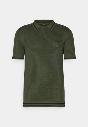 Olive green polo shirt made from a knitted fabric, featuring a textured pattern, black striped accents on the collar and sleeves, and a logo patch.