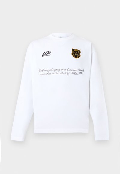 Λευκό πουκάμισο με μακριά μανίκια, με μαύρο κείμενο γραμμένο σε σενάριο στο ύψος του στήθους και δύο λογότυπα: μαύρο έμβλημα Off-White® και κίτρινη-μαύρη κονκάρδα μπροστά.