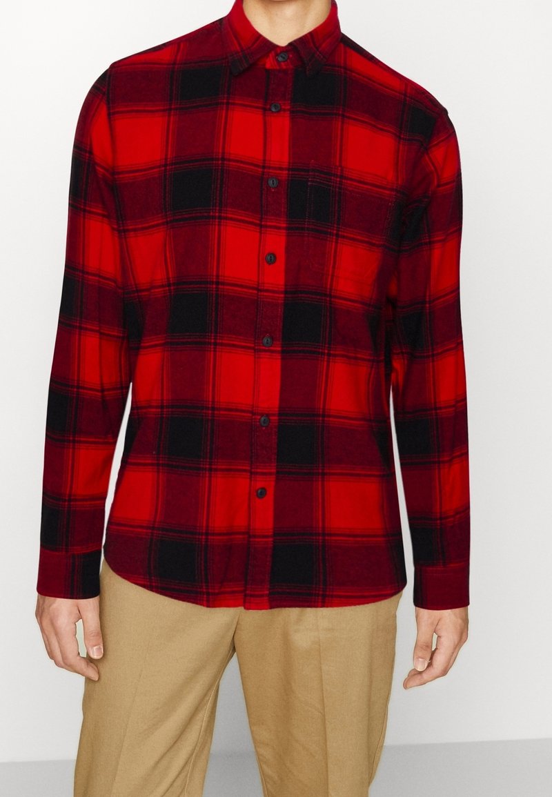 Rode en zwarte geruite flanellen shirt met lange mouwen, knoopsluiting aan de voorkant en puntige kraag; gemaakt van zachte stof met een gladde textuur.