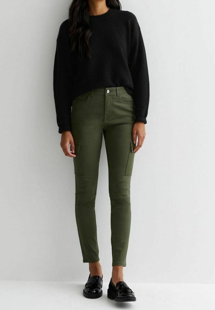 Jersey negro texturizado con cuello redondo, combinado con pantalones cargo ajustados en color verde oliva con bolsillos laterales, llevados con mocasines negros.