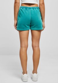Turquoise cotton shorts with an elastic waistband and rolled hems, featuring a smooth texture and a relaxed fit.