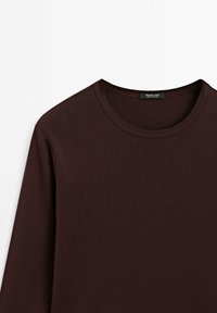 Burgundy long-sleeve T-shirt with a round neckline, made of soft, textured fabric. Features flat seams and a label at the collar.