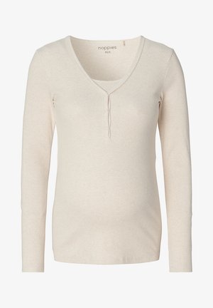 Licht beige langwerpige zwangerschapstop met lange mouwen van zachte, ribbelstof. Heeft een V-halslijn met drie knopen en fijne stiksels langs de rand.