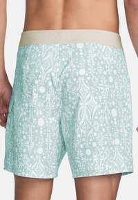 Zwemshorts in licht muntgroen met een wit abstract patroon en een contrasterende beige elastische tailleband. Inclusief een zijzak.