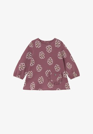 Vestido de manga larga para niño pequeño en tono malva con patrones de flores beige y blancas, y un pequeño bolsillo con volantes que incluye un dije en forma de corazón.