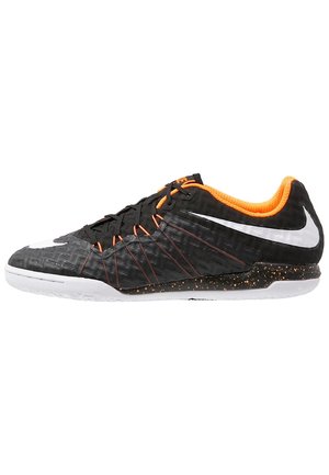 Schwarzer und orangefarbener Nike Hallenfußballschuh in niedriger Ausführung mit weißem Swoosh-Logo und schwarz gesprenkelter Sohle auf weißem Hintergrund.