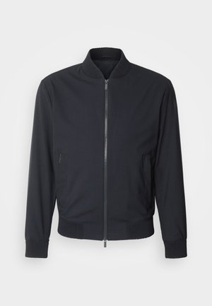 Zwarte bomberjack met ritssluiting aan de voorkant, ribbelkraag en -manchetten. Voorzien van zijzakken en een gladde, matte textuur. Eenvoudig en modern ontwerp.