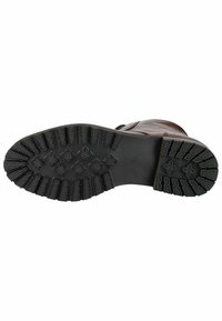 Suela de goma negra con textura para agarre, y parte superior de cuero marrón. El diseño incluye una puntera redondeada y costuras decorativas.