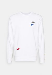 Sudadera de cuello redondo de manga larga blanca con cuatro logotipos de Nike bordados en negro, azul, rojo y verde en el pecho, la parte inferior delantera y el puño.