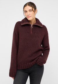 Burgunderfarbener Strickpullover mit hohem Kragen, halbem Reißverschluss und geripptem Saum. Verfügt über ein strukturiertes, grob gestricktes Design für zusätzliche Wärme.