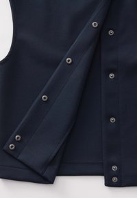 Marineblaues Westchen aus strukturiertem Stoff, mit silbernen Druckknöpfen in der Front und einem klaren, strukturierten Schnitt.