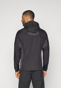 Schwarze Outdoor-Jacke mit Kapuze, die kontrastierende graue Seitenpaneele und strukturierte Rückendetails aufweist. Leicht, athletischer Schnitt und funktionales Design.
