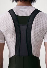 Atletisch bodysuit met een witte gaas bovenkant met een textuurpatroon, zwarte gaasbanden en een groene onderkant.