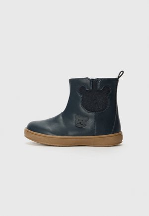 Bottines en cuir bleu marine avec des accents en forme d'ours, semelle en caoutchouc et une pièce texturée bleu foncé à l'arrière ; fermeture éclair.