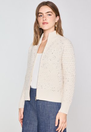 Cardigan lavorato a maglia color crema con un motivo testurizzato, bordi a coste e tasche laterali. Presenta una zip frontale e un colletto alto.