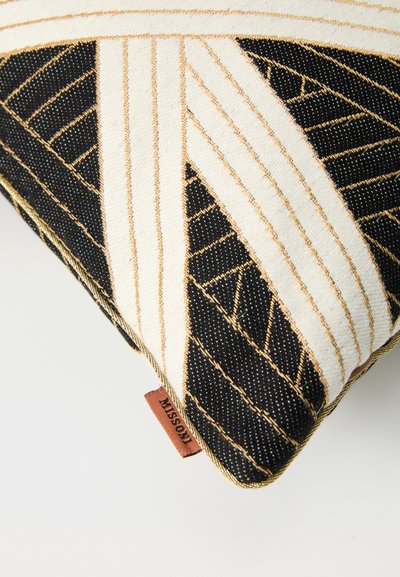 Rectangular cushion featuring a black and white geometric pattern with gold stitching. Includes a brown brand tag at the edge. Soft texture.