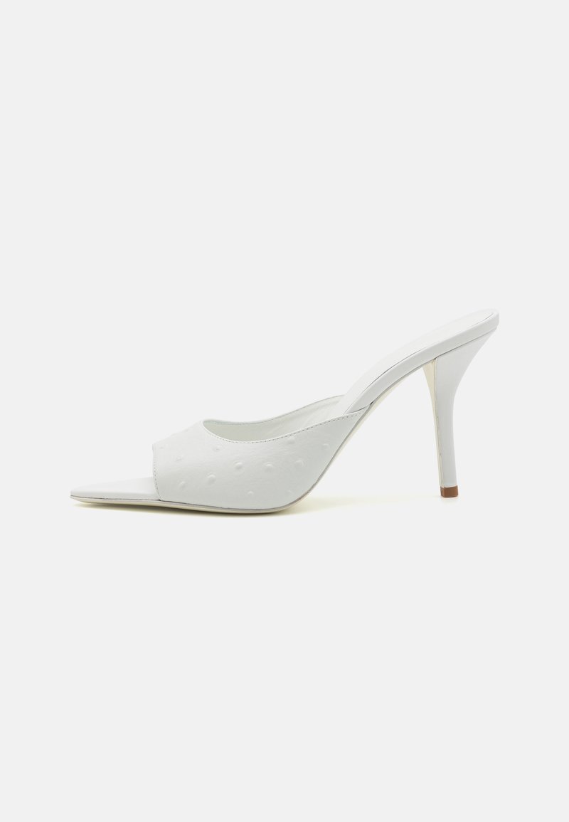Witte open teen mule met een gestructureerd oppervlak, puntige voorkant en een hoge stiletto hak met een contrasterende bruine punt. Minimalistisch ontwerp.