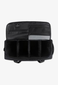 Μαύρη ταξιδιωτική τσάντα με ευρύχωρο, διαχωρισμένο εσωτερικό. Διαθέτει λείο ύφασμα, πολλαπλές τσέπες με φερμουάρ και επίπεδη βάση για σταθερότητα.