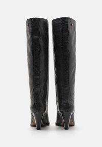 Black knee-high boots with a snakeskin texture, pointed toe, and subtle gold hardware accent on the side. Stiletto heels.
