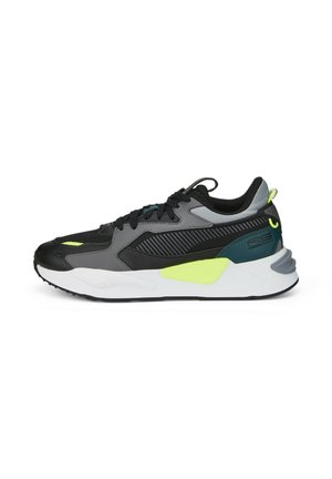Scarpe da ginnastica nere e grigie con accenti verde neon. Caratterizzano una parte superiore testurizzata, una suola bianca spessa e elementi di design a contrasto.