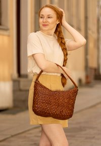 Borsa a tracolla in pelle intrecciata marrone con una forma strutturata, dotata di una tracolla resistente e una superficie testurizzata. La borsa è di media grandezza con dettagli sottili.