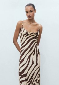 Robe maxi en tissu lisse avec un motif rayé zèbre marron et beige, des fines bretelles et un col drapé.