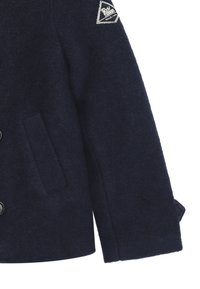 Cappotto di lana navy con un patch triangolare con logo, chiusura a bottoni, tasche laterali e tessuto texturizzato. Design classico con linee pulite.