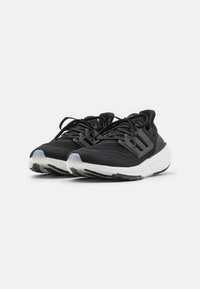 Baskets noires de sport avec une tige en mesh, un système de laçage et une branding à trois bandes. Comprend une semelle intermédiaire blanche et une semelle extérieure à crampons noire.